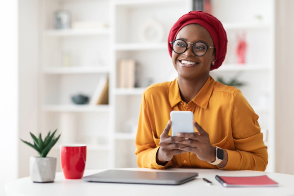 Black woman happily holding her phone engaging with her audience. 