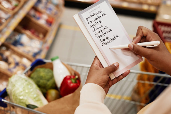 black woman crossing off groceries