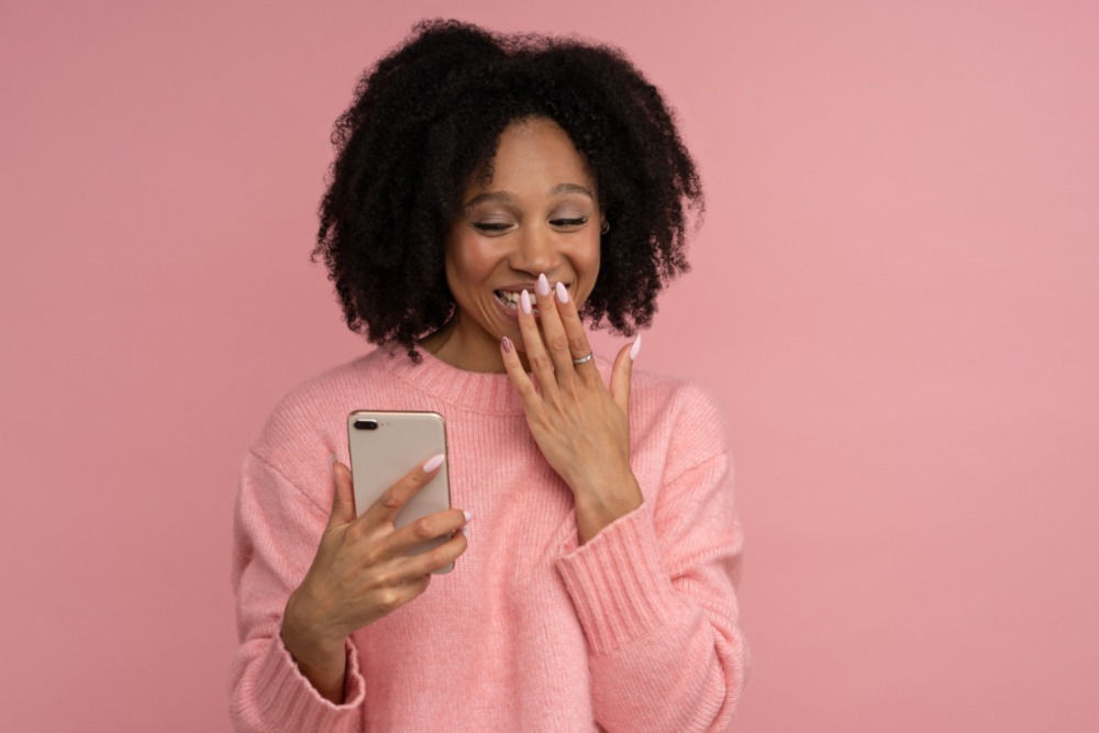 black woman giggling looking at phone