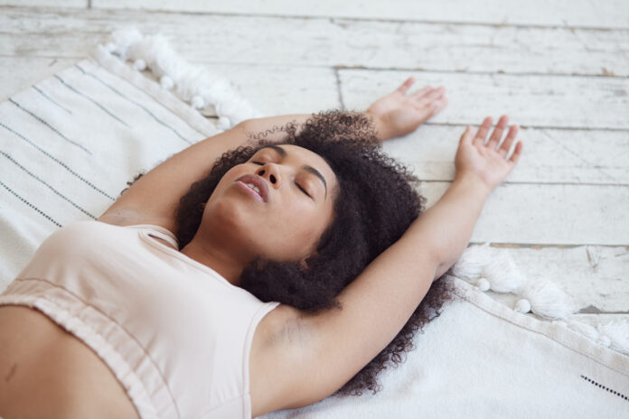 Black woman doing yoga and breathwork.