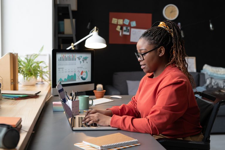Black woman working on her business visibility at her computer.