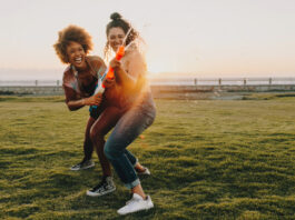 Two women having fun outside of work with waterguns.