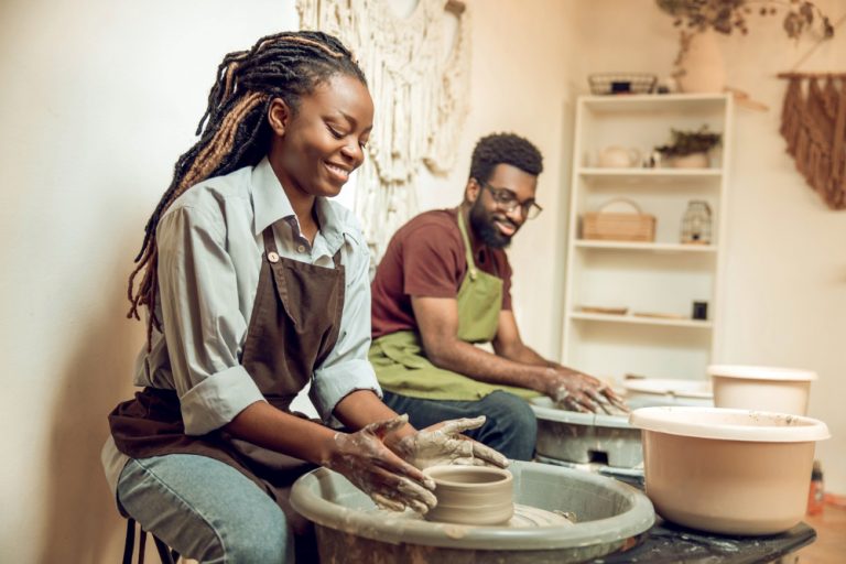 Black woman and man in pottery class as one of the creative hobbies.