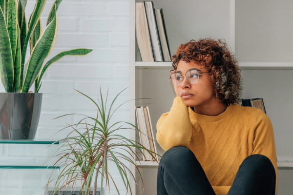 Young woman looking out of window in fear of letting go. 