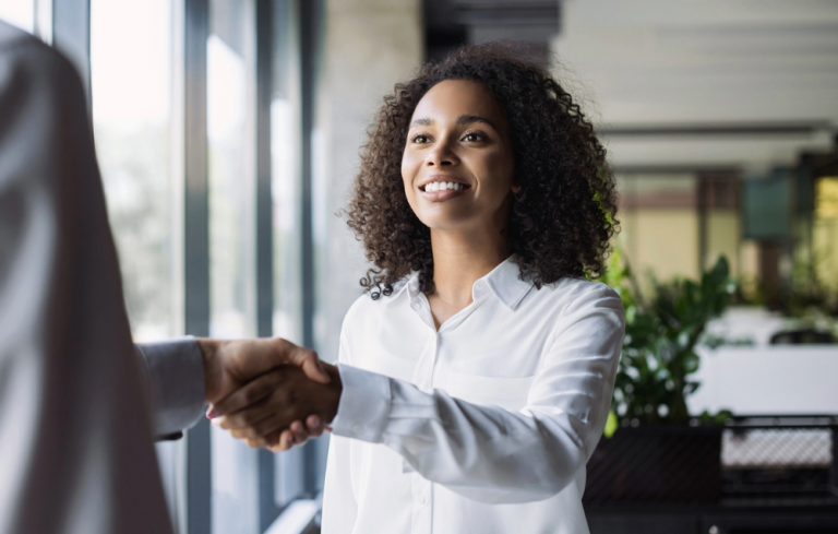 Black woman shaking hands after an interview she found on SwagHer Jobs.