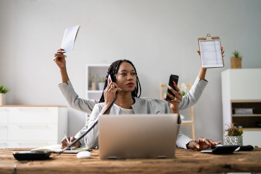 Black woman at desk in need of work-life balance.
