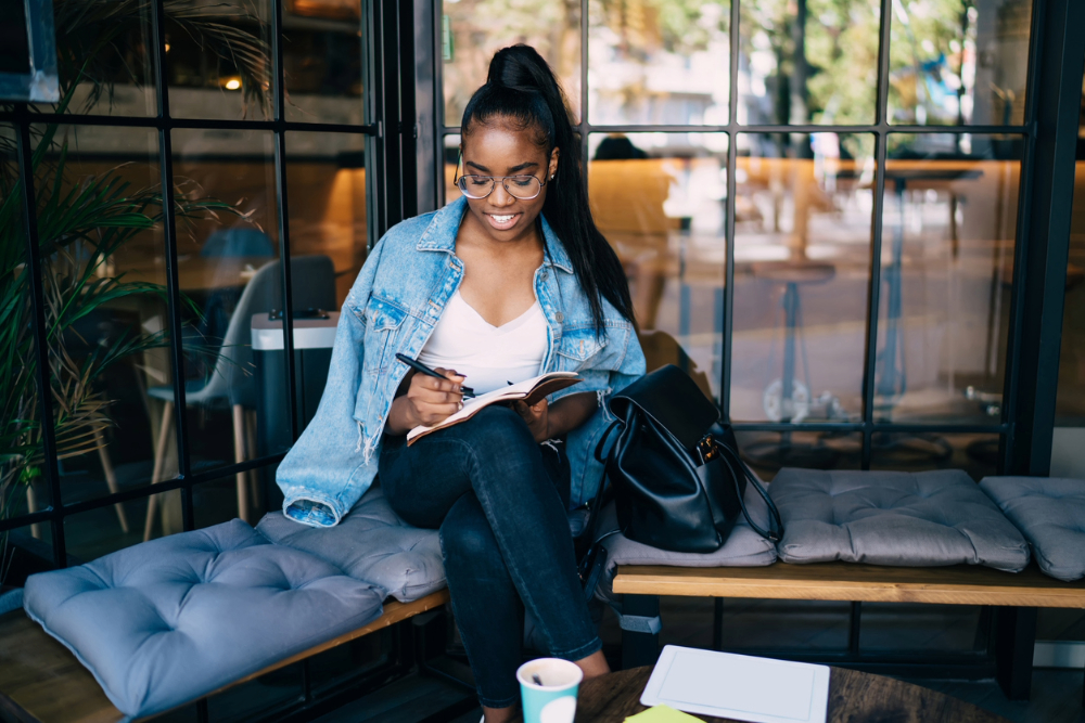 Black woman journaling while practicing self-compassion.
