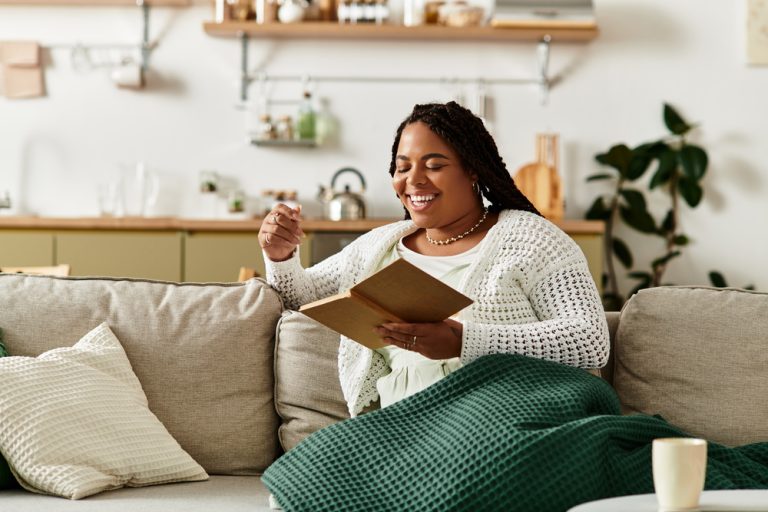 Black woman practicing rest on sofa while reading.